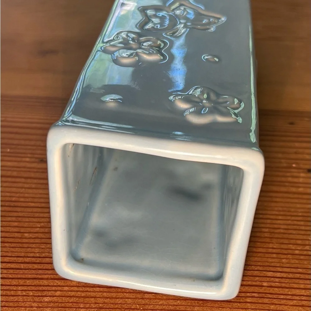 Small baby blue bud vase. With “butterflies and flowers.”